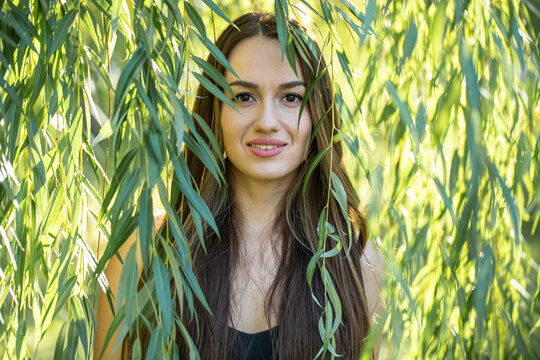 Portrait of a young beautiful woman posing in willow foliage