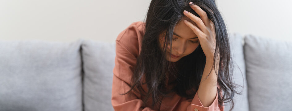 Stressed female feeling depressed and lonely on the sofa in the house.