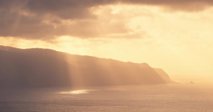 Golden sun rays over ocean cliffs in Madeira island Portugal Dramatic golden sunset sky with sunbeams breaking through clouds