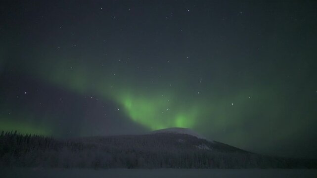 Aurora shimmering above snowy fells and forests, real time
