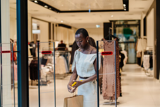Elegant African American Shopper Navigating Through Bright Shopping Mall