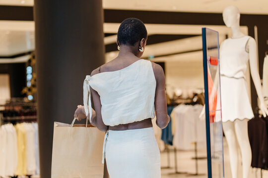 Back View of Elegant Black Woman with Craft Bag Walking in Shopping Mall