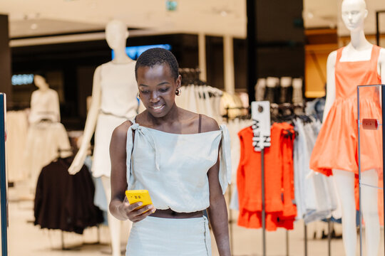 Joyful Black Woman Checking Social Media While Shopping in Retail Mall