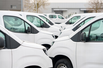 White delivery vans are parked in rows. Commercial fleet of vehicles © scharfsinn86