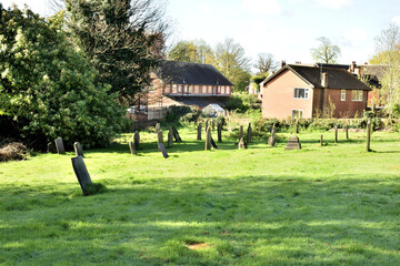 Sun-dappled glade in the historic Bulwell churchyard featuring a leaning stone Celtic cross and old headstones surrounded by mature trees in spring © ASCOCD