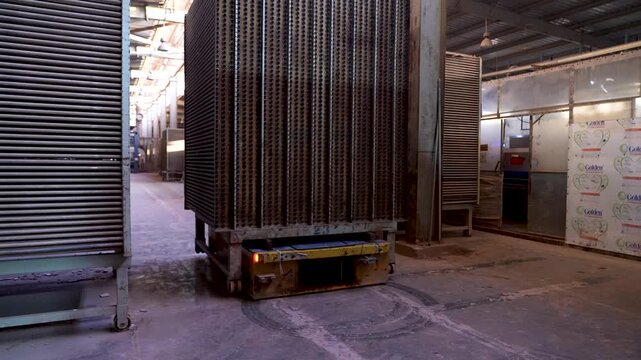 Industrial robot moving tile racks forward in automated ceramic factory production line
