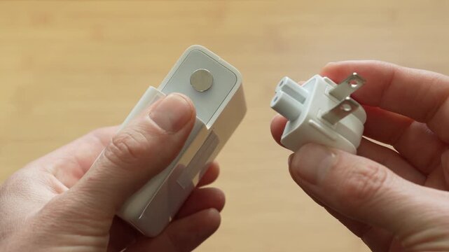 Close up of male hands attaching detachable power plug to adapter. Concept of electricity connection, device setup, power supply and user instruction.