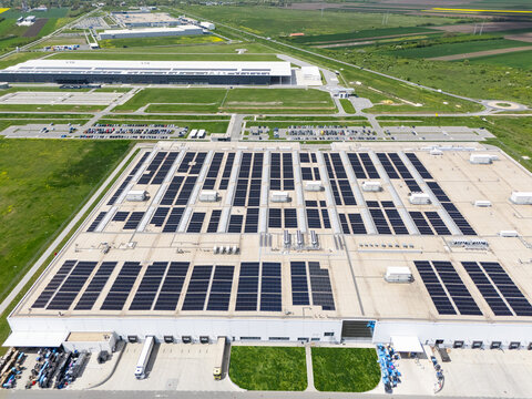Aerial view of a modern factory with solar panels and energy storages on the roof