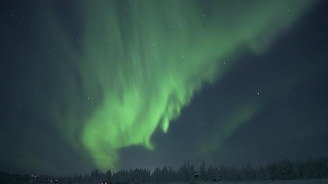 Northern lights above snow covered forest and cabins, real time