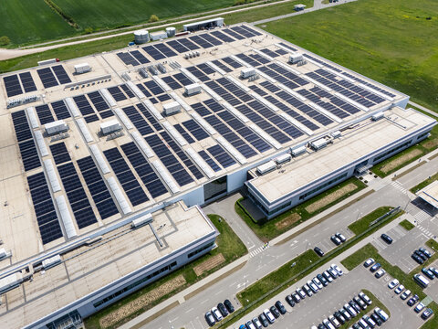 Aerial view of a modern factory with solar panels and energy storages on the roof