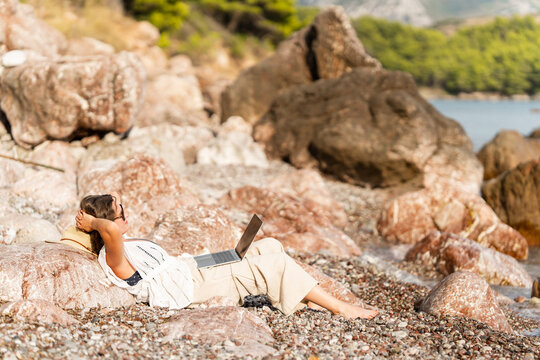 Woman using laptop on the sea coast at summer