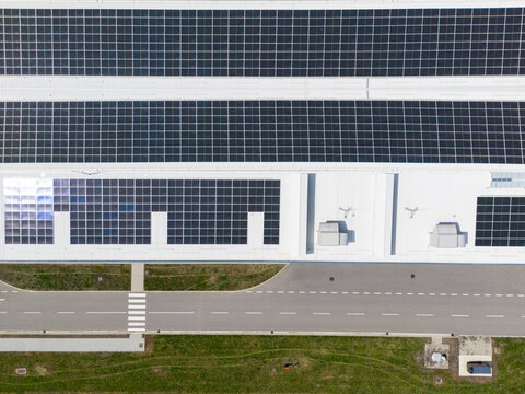 Aerial view of a modern factory with solar panels and energy storages on the roof