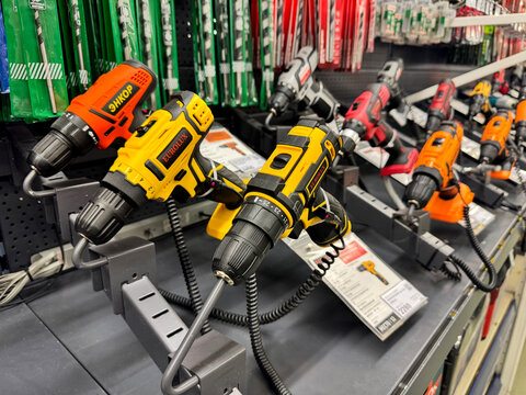 Barnaul, Russia, 06.06.2025: Cordless power drills on display at a hardware store shelf. Yellow Eurolux and orange Enkor drill models are showcased for sale.