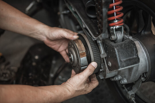 Mechanic hands assembling a motorcycle rear clutch bell housing during CVT maintenance.