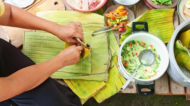 Traditional Indonesian cook preparing garang asem with banana leaves