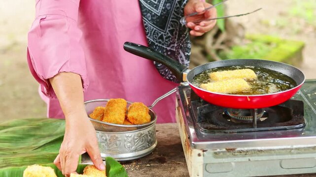 Woman deep frying traditional Indonesian risoles in hot oil