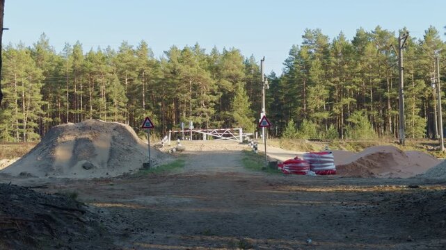 Morning scene featuring motocross riders jumping on sandy terrain with trees. Highdefinition image capturing motocross athletes leaping over mounds in wilderness setting during daylight