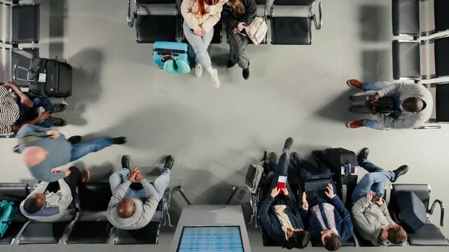 Friends in airport checking departure board for timetable, traveling together, top down view. Travel buddies looking at FIDS screen schedule, catching plane for holiday trips, high angle shot