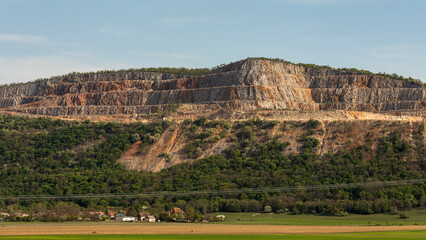 Naklejka premium Large rock formation with steep cliffs and plants in the background near a small town in daylight