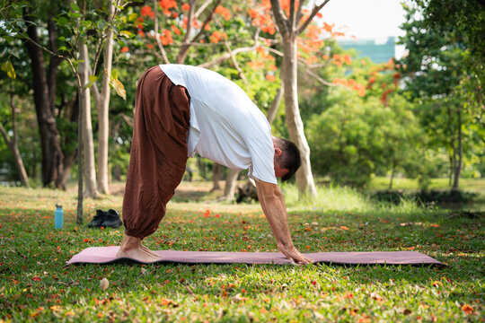 Outdoor yoga man performing forward fold in park stretching hamstrings improving flexibility and balance during fitness training and wellness routine