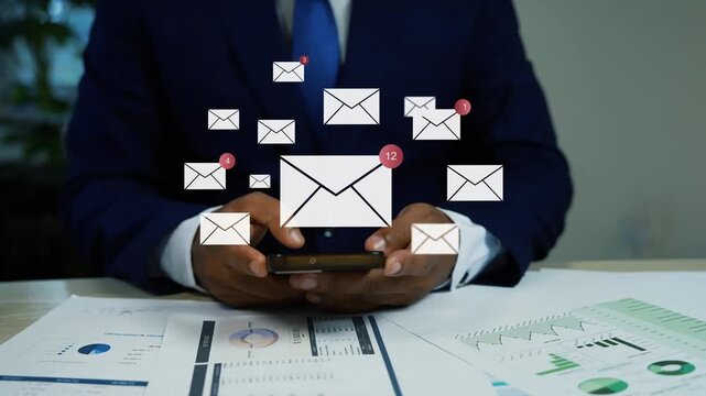 Businessman using a smartphone with hologram mail icons animation, Businessman checking email notifications on smartphone at office desk