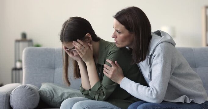 Loving mother comforting upset teen daughter, stroking her, giving parental advice, discussing personal troubles, share emotional support during conversation at home. Trustworthy family relationships