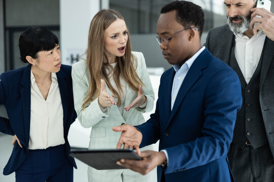 Diverse business professionals debating during a stressful office meeting, discussing disagreement and strong emotions