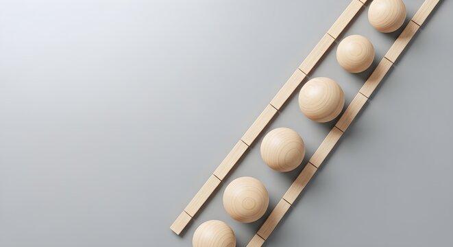 Five plain wooden spheres positioned on parallel wooden rails forming ladder steps over light grey background representing progress development and growth throughout business life.