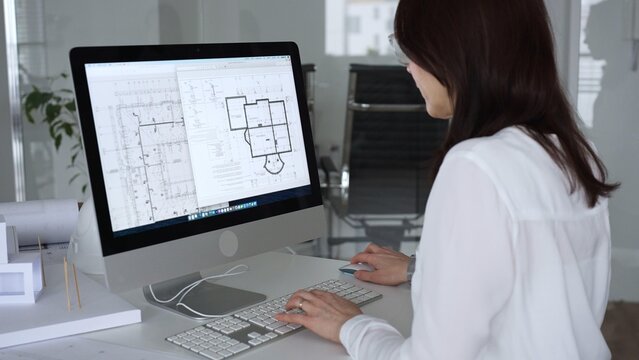 Woman architect drawing building plans on computer, designing modern housing project with cad software. Business and architecture concept