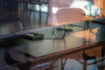 Fotobehang Horeca Elegant Restaurant Table Setting Seen Through Window Reflections, Empty Cafe Interior with Glass, Flower Vase, Soft Light and Moody Bokeh  © Edijs