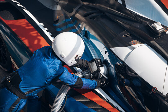 Team Mechanics refuel race car During a High-Speed Pit Stop in the Midst of an Endurance Race	