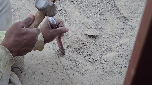 Laborers employ traditional hammer and chisel methods for slab breaking and waterproofing. This essential manual technique is widely used in home repairs, construction, and artisanal stone carving.