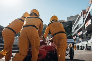 Fototapete Formel 1 Team mechanics pushing a historic Formula 1 car along the pit lane during a classic racing event  © UnPinky
