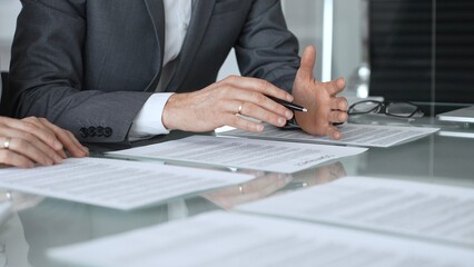 Obraz premium Business executive hands gesturing over contract on glass table during formal office meeting negotiating legal agreement terms. Business people concept