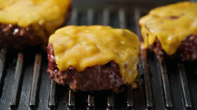 frying beef patty with melted cheese on a hot grill . Melting cheese on a beef patties grilling a hot barbecue grill. Making cheese burger in a grill. hamburger patties with cheese grilling on a barb