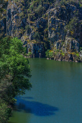 Obraz premium a serene blue river Zêzere winding through a dramatic rocky canyon enveloped by vibrant green forest and steep stone cliffs