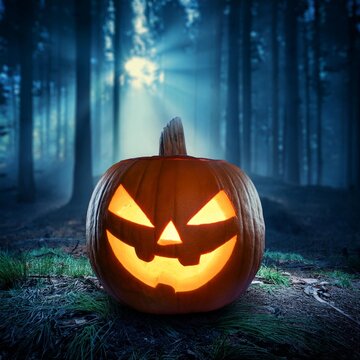 Spooky carved orange jack-o-lantern with a scary smile on a dark wooden table background for a horror autumn halloween holiday season decoration