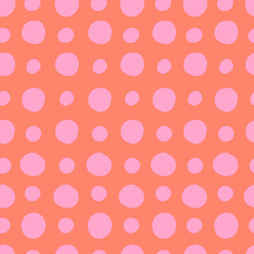 Pink polka dots on red background seamless pattern. Large and small hand-drawn circles. Cute pattern. Abstract vector background.