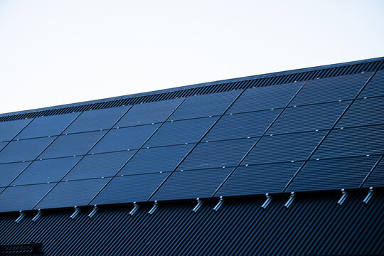 Solar panels installed on modern building roof under clear blue sky.