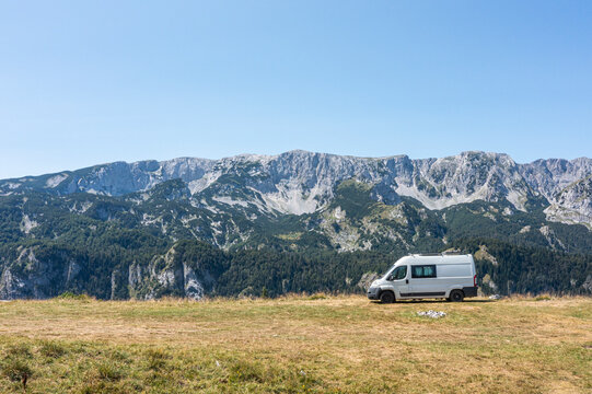 Mountains in the background with a van parked on grassy land during a clear day on Maglic mountain in Bosnia and Herzegovina