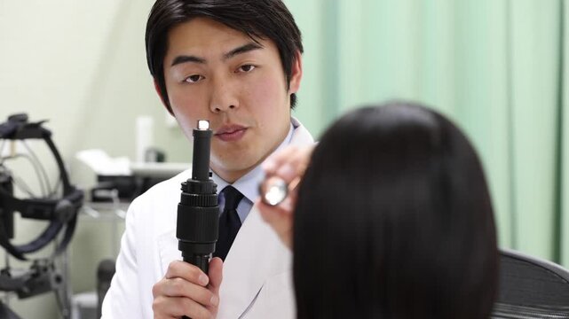 ペンライトで目の状態を診察する眼科医と女性患者の診療シーン