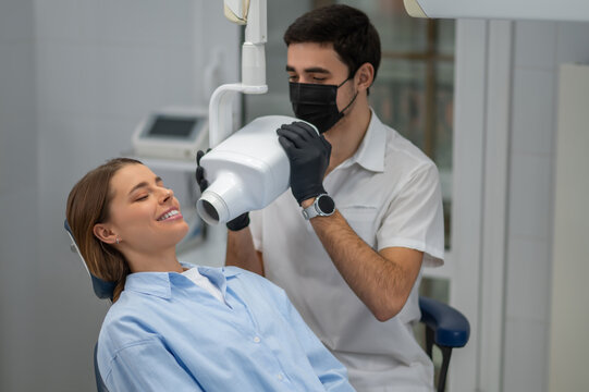 Dentist adjusting x-ray machine for patient