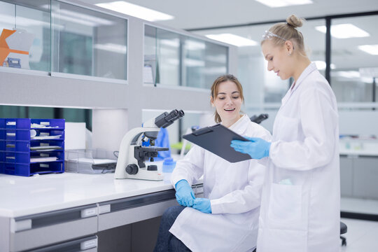 Scientists collaborate in a modern laboratory, sharing results and analyzing data on a tablet