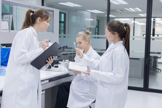 Three scientists in lab coats engage in discussion in laboratory