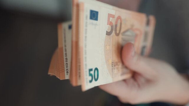 Close Up Hand Holding Thick Stack Of Orange Fifty Euro Banknotes