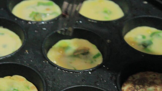 Cooking mini omelets with green onions in a traditional round mold pan
