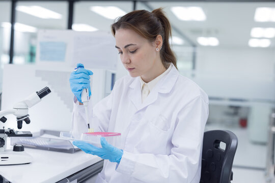Laboratory technician conducts experiments with test tubes and microscope in a modern research facility