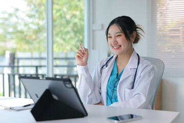 Happy asian medical professional giving a virtual telemedicine consultation to a patient using modern technology from an office © amnaj