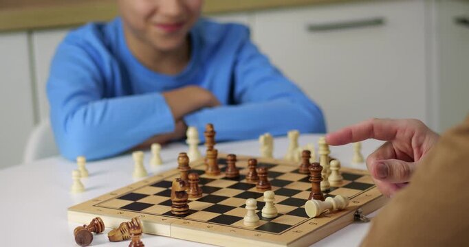 Boy plays chess game strategy. Kid moves piece in chess game match. Child learns logic through chess game. Intellectual hobby develops mind. Smart thinking wins match. Focus creates serious mood.