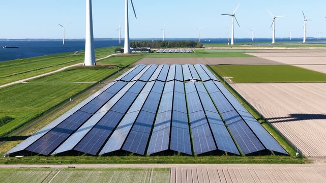 Aerial drone view of solar panels and wind turbines in a renewable energy farm. Sustainable green power station for clean electricity production and environmental technology infrastructure.